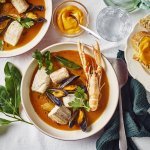 Een heerlijk kleurrijk bordje bouillabaisse staat op tafel. Wij maakten hem met topproducten van hier. Er ligt een donker groene linnen servette langs en bordje stukjes brood en verse rouille.