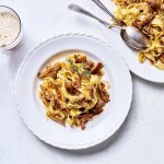 Op tafel staat een wit bord gevuld met tagliatelle en konijnenragout. Er staat een biertje langs, aangezien de ragout gemaakt is met Belgisch bier. 