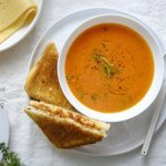 Een heerlijke kom soep staat klaar op tafel in een wit kommetje. Wij serveren hem met een toast van kaas en tomaatjes. Een heerlijke en voedzame lunch.