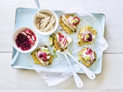 Rosties liggen geschrankt op een dienschaaltje in licht blauwe kleur. Hierop ligt een wit boterpapier waar de rosties op afgewerkt werden. Er staan ook nog twee potjes in beeld met de restjes van de makreel, radijsjes en zoetzure rode ui. 