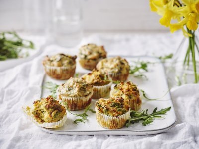 Hartige cupcakes op een dienplateau gepresenteerd. Achteraan staat een vaasje met Narcissen te schitteren.