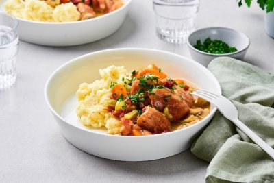 Op tafel staan twee uitgeschepte porties van het hoofdgerecht. Een schep heerlijke puree met kalfsfricassee. In de fricassee zitten spekblokjes, selder en wortelstukjes. Het gerechtje is afgewerkt met verse peterselie. Er ligt een licht groene servette langs en wit bestek.