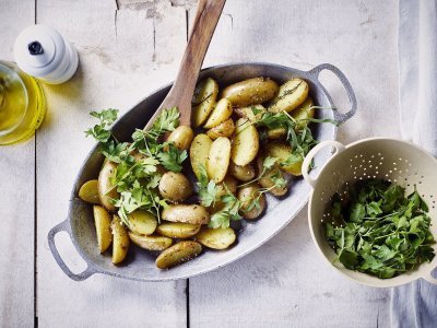 Krieltjes uit de oven in licht blauwe ovenschaal met verse kruiden, peper en zout. 