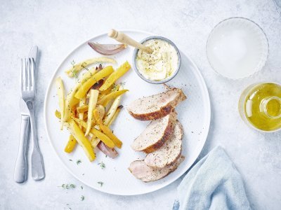 Groot wit bord met 4 stukjes versneden varkenshaasje, geroosterde pompoen en zoete aardappel. Er staat een klein grijs potje op het bord met truffelmayonaise is en houten lepeltje. Het bordje is afgewerkt met verse tijmblaadjes en een licht blauwe servet langsheen het bord. 