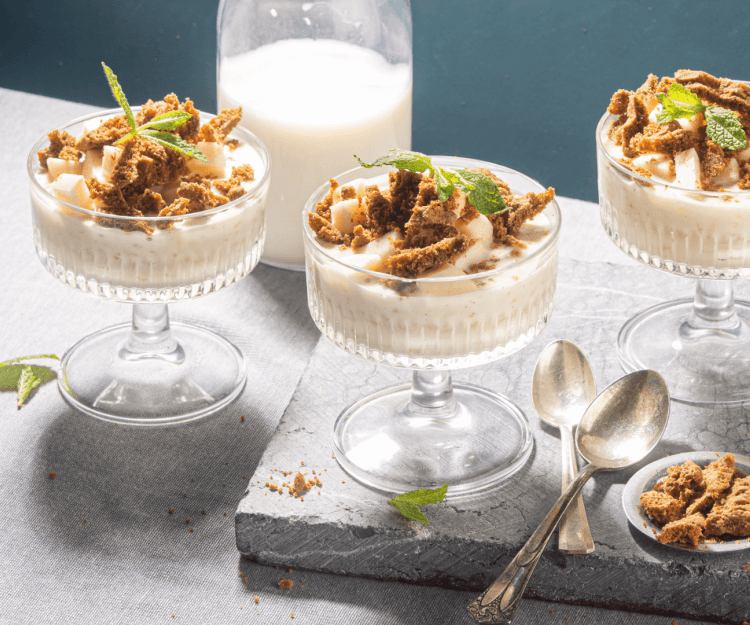 Rijstpap geserveerd in mooie champagnecoupes zorgen instant voor een dessert met sterallures. Hij kreeg een topping mee van appelblokjes en bastognekoekjes voor een crunch. Er zijn 3 glaasjes in beeld. 