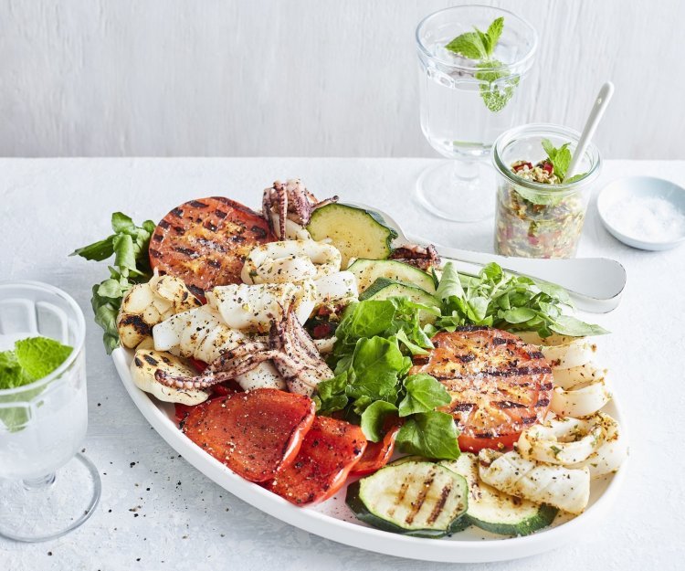 Een grote schaal gevuld met de salade van inktvis en gegrilde groenten zoals tomaten, paprika en courgette. Een topper in het zuiden boordevol zomerse ingrediënten van bij ons. 