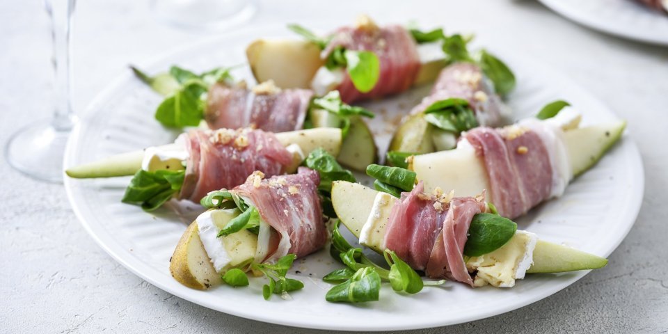 Op groot wit bord ligt het hapje geserveerd, de partjes peer met een stukje brie omwikkeld met een sneetje gandaham. Simpel gerechtje, boordevol smaak en kleuren. De groene verse waterkers maakt het volledig af.