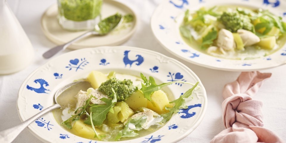 Een wit bord met blauwe kipjes op de rand is gevuld met heerlijke verse kippensoep. Het is een echte maaltijdsoep, met stukjes kip, aardappelen en prei. We werkten de soep af met een scheutje room in het bord en schep rucolapesto. Echt lekker! 