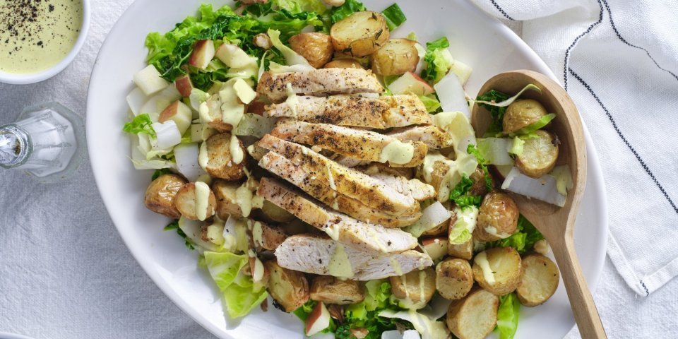 Een groot bord is rijkelijk gevuld met stukjes groenten, fruit, aardappel en gebakken kip. Hij is afgewerkt met een heerlijke currydressing. Schep maar op, zou ik zeggen. 