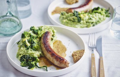 Op tafel staan twee borden gevuld met een schep erwtenpuree en savooikool. We serveren hem als een echte Vlaamse klassieker met een braadworst en een schep mosterd.