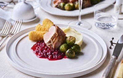 Op een wit bord is dit feestelijk gerecht geserveerd. Eerst een schepje pastinaakcrème, met hierbij de veenbessensaus, de kroketten, spruitjes en het stukje varkensvlees. Ten aanval.