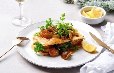 Een feestelijke kalfsfricassee staat op tafel, de ster van het menu. De fricassee ligt tussen twee knapperige vellen bladerdeeg met verse kervel en een partje citroen. 