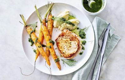 Een heerlijk goudgeel gebakken stukje varkensvlees ligt op een wit bord. De bijgerechten liggen er langs te blinken, denk maar aan oranje wortellen in zijn geheel en toefjes venkelpuree. Hier en daar werd wat kruidenolie gedrupt. 