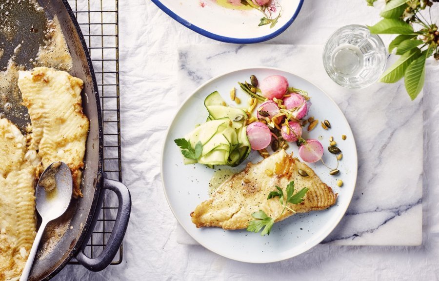 Een rond bord is gevuld met het gerechtje. De grote ovenschaal staat op tafel met al een portie uitgeschept. De radijsjes zitten in een ander ovenschaaltje en staan eveneens op tafel. De radijsjes en courgette zorgen voor een mooie kleur in het gerechtje bij de vis.