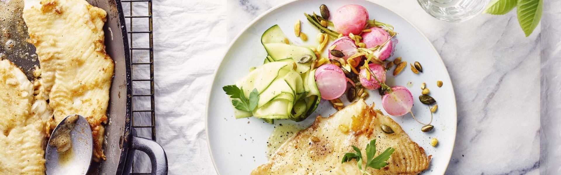 Een rond bord is gevuld met het gerechtje. De grote ovenschaal staat op tafel met al een portie uitgeschept. De radijsjes zitten in een ander ovenschaaltje en staan eveneens op tafel. De radijsjes en courgette zorgen voor een mooie kleur in het gerechtje bij de vis.