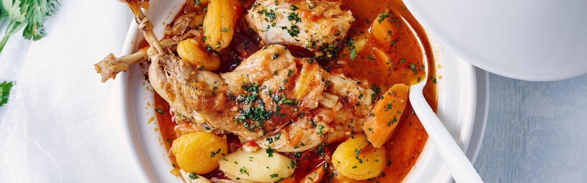 Een witte tajine staat op tafel met deksel open, deze tajine is gevuld met heerlijke producten van bij ons, denk maar aan konijn, aardappel, wortelen, pastinaken en tomaten. Dit in combinatie met smaakmakers uit het Midden-Oosten, een toppertje!